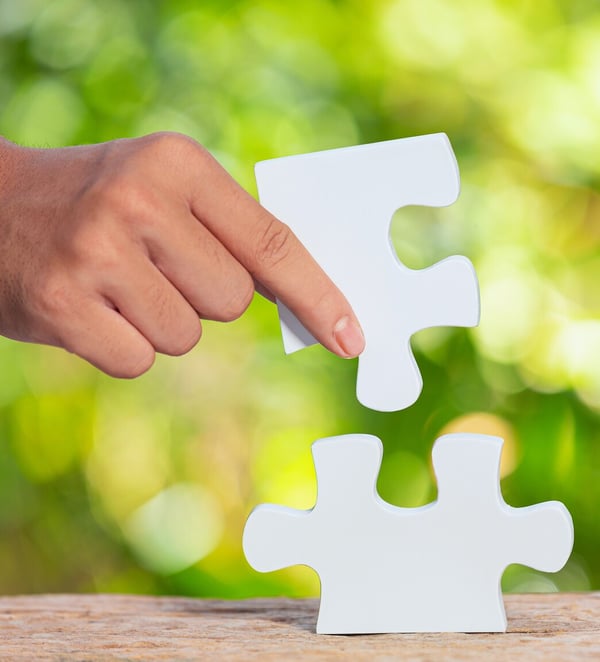 Dłoń układająca białe puzzle